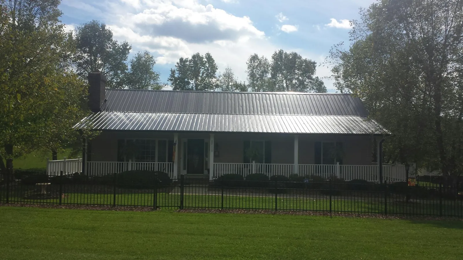 Gray metal roof on a brick ranch with a full width front porch — Gutter Guard Installation work by our crew in Harwinton